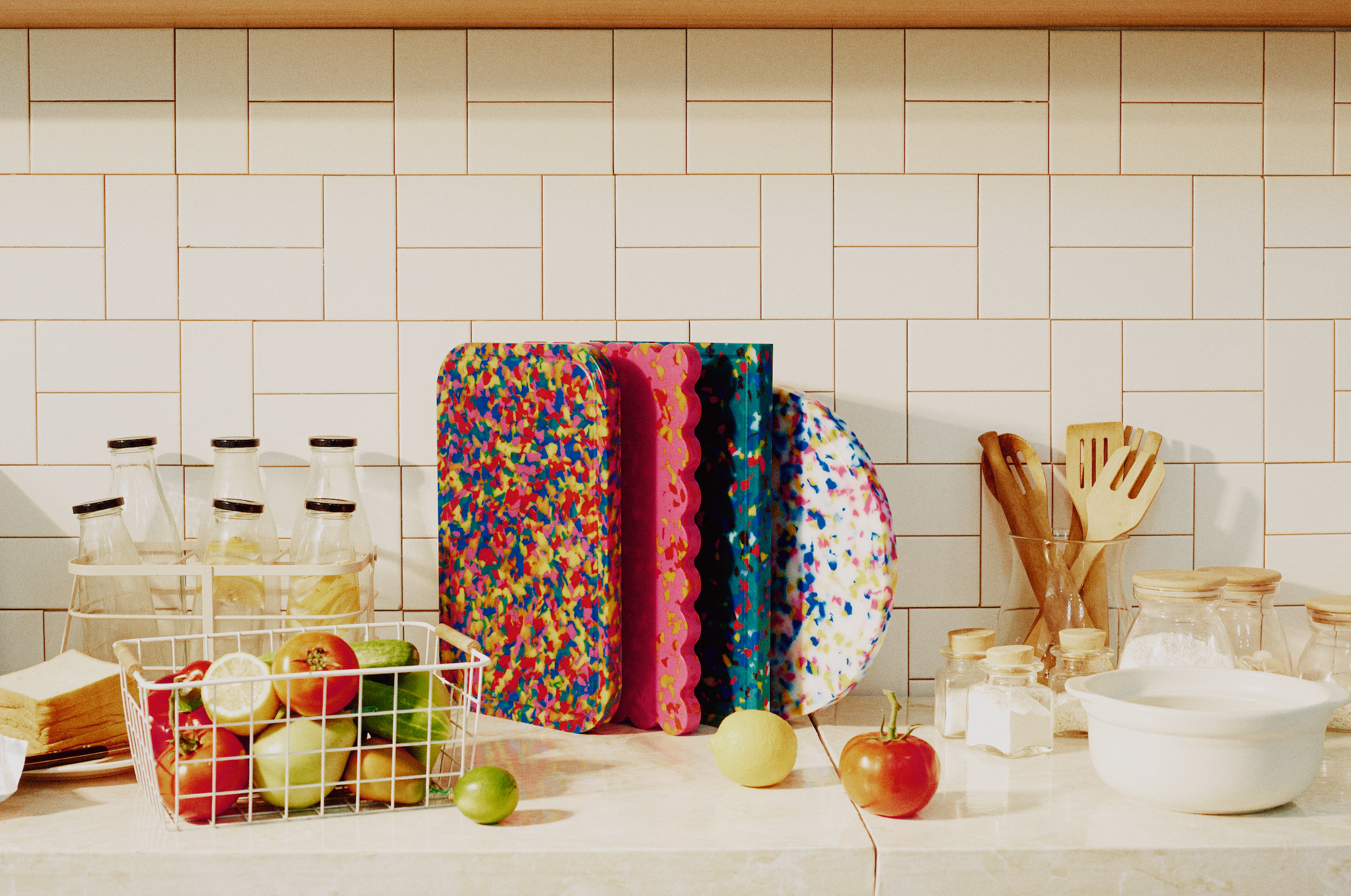 Set of Kiyomi cutting boards—Carnival, Cherry, Lagoon, and Skye—stacked on a kitchen counter with fruits and jars