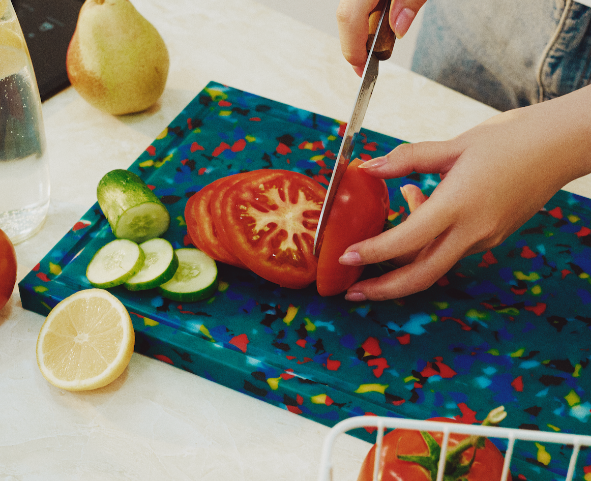 Lagoon rectangular cutting board in green with colourful speckles, used for chopping tomatoes and cucumbers